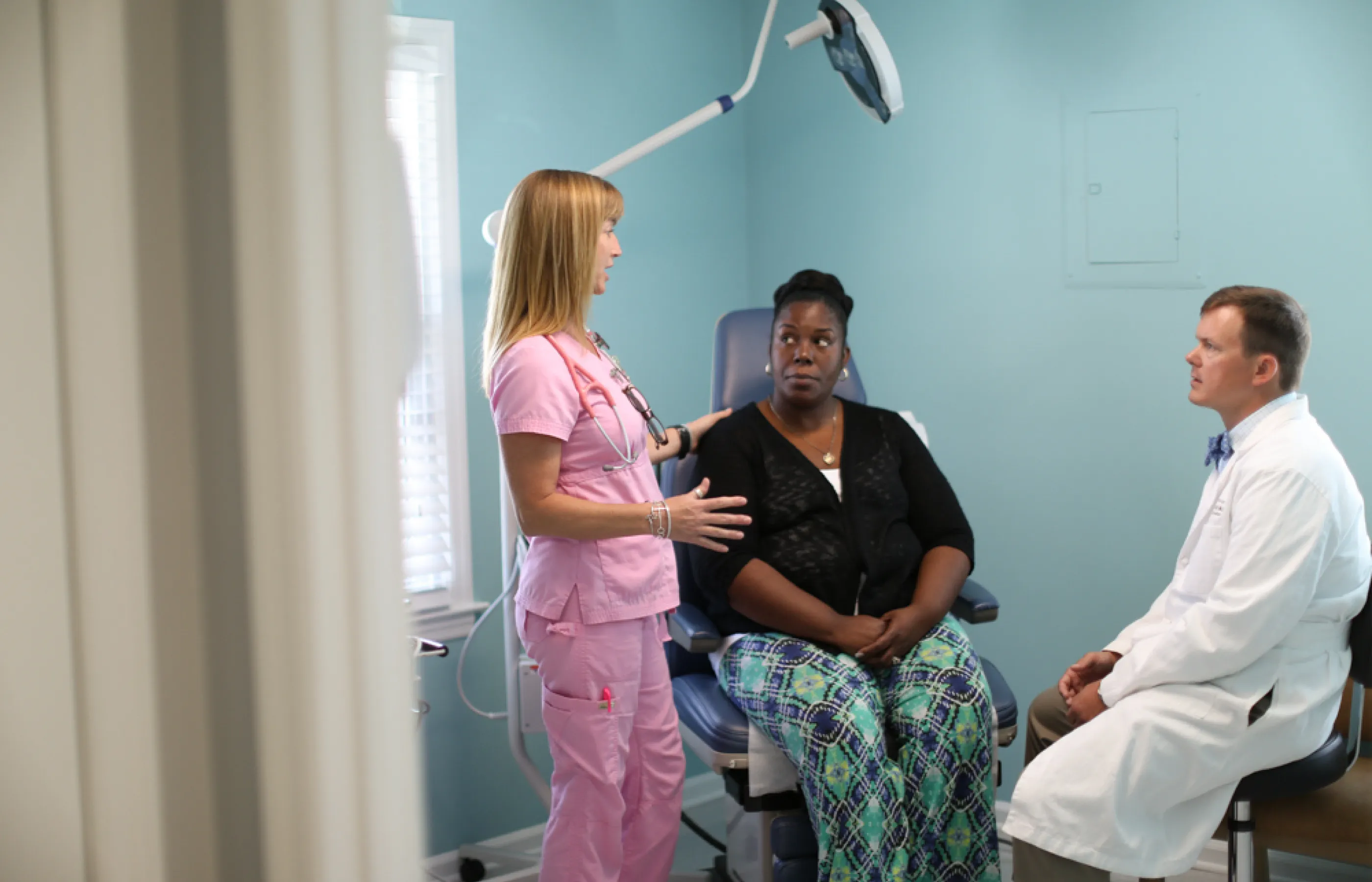 A Novant Health patient, doctor, and nurse are all together in exam room talking. 