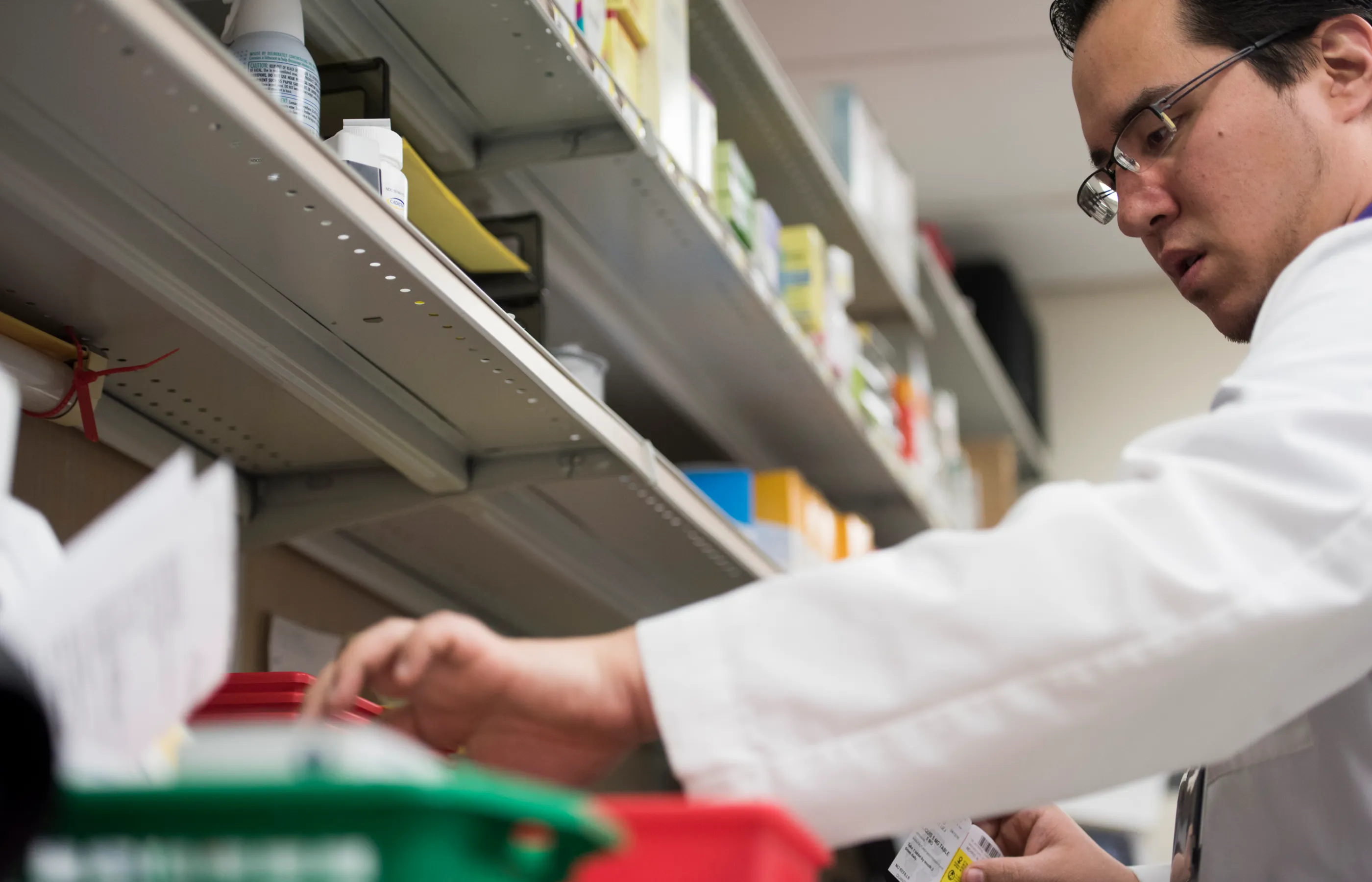 A Novant Health pharmacists, who is wearing a lab coat, is sorting through medication.