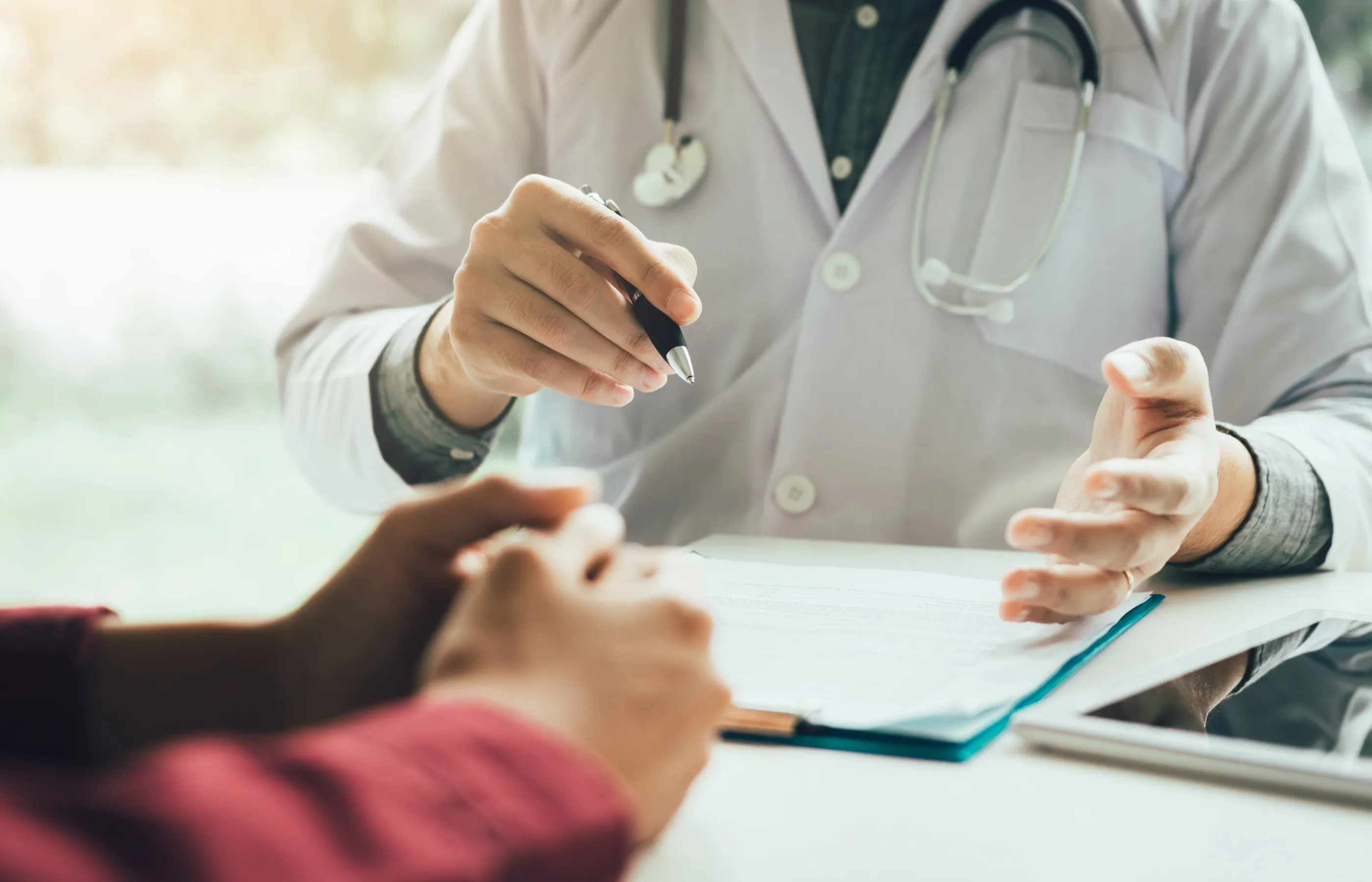 Hands of a patient and provider as they discuss clinical results and forms. 