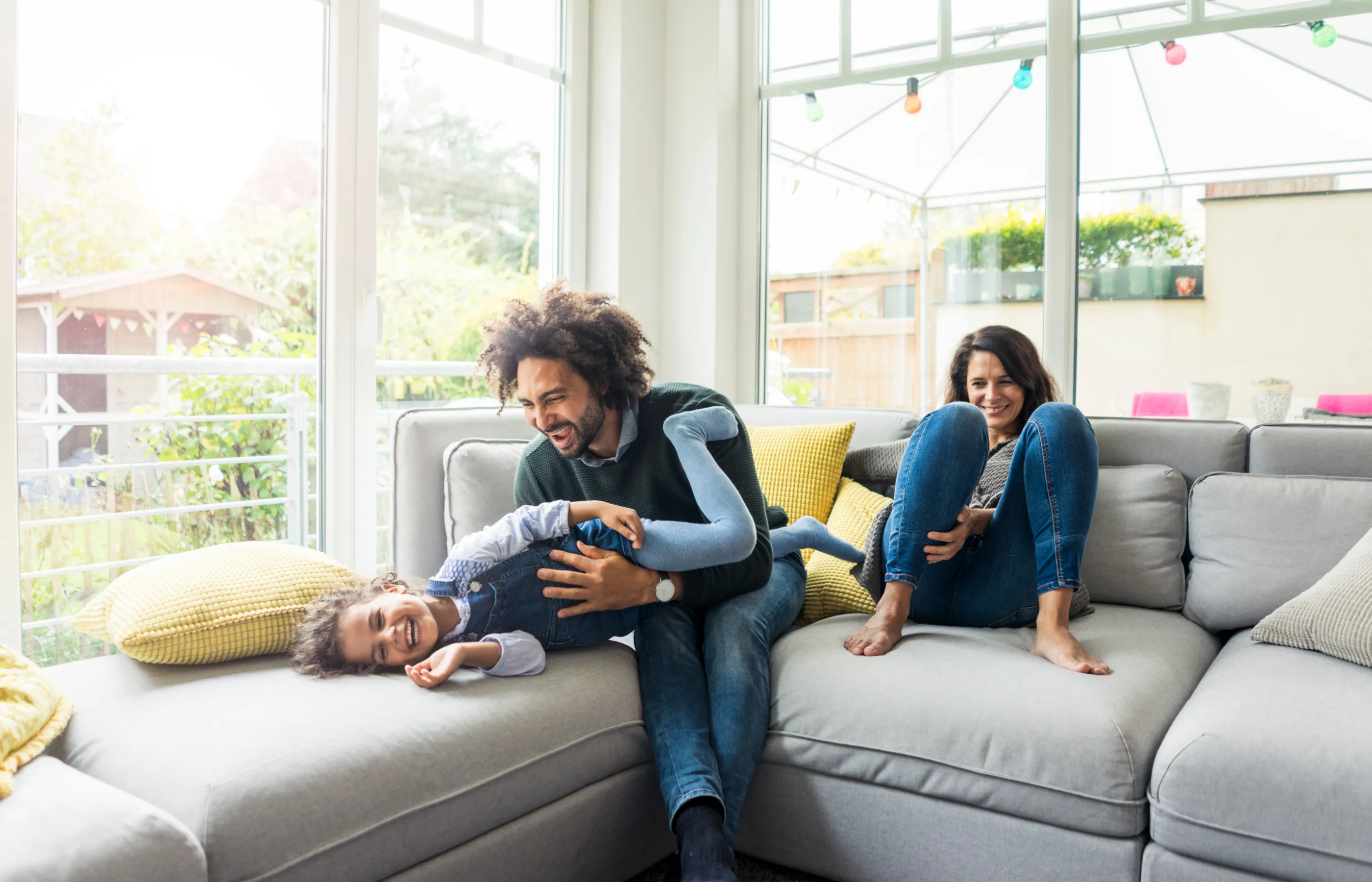 Parents sitting in their family living room smiling and laughing with child.