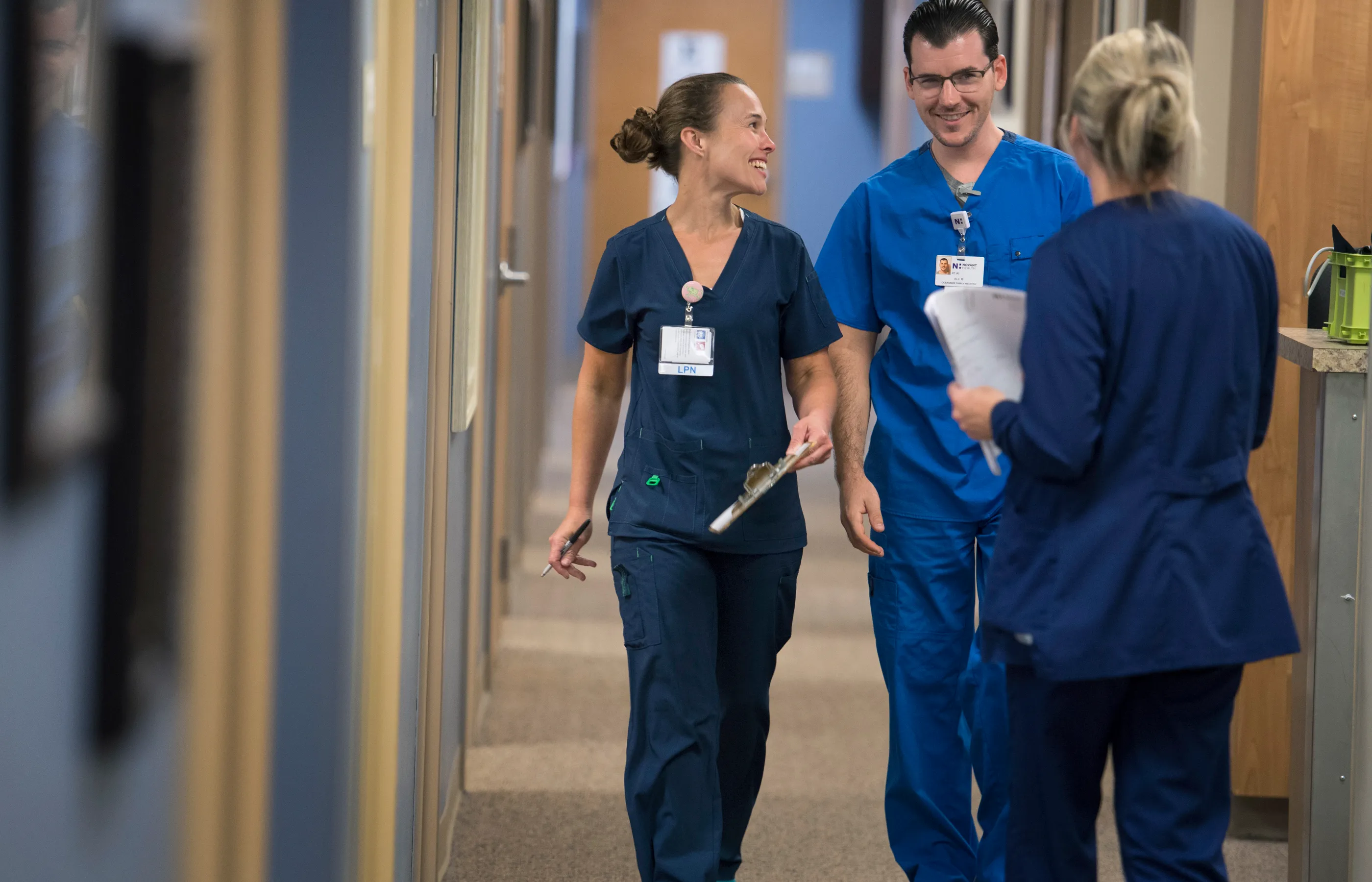 Three team members smiling while walking down hall 