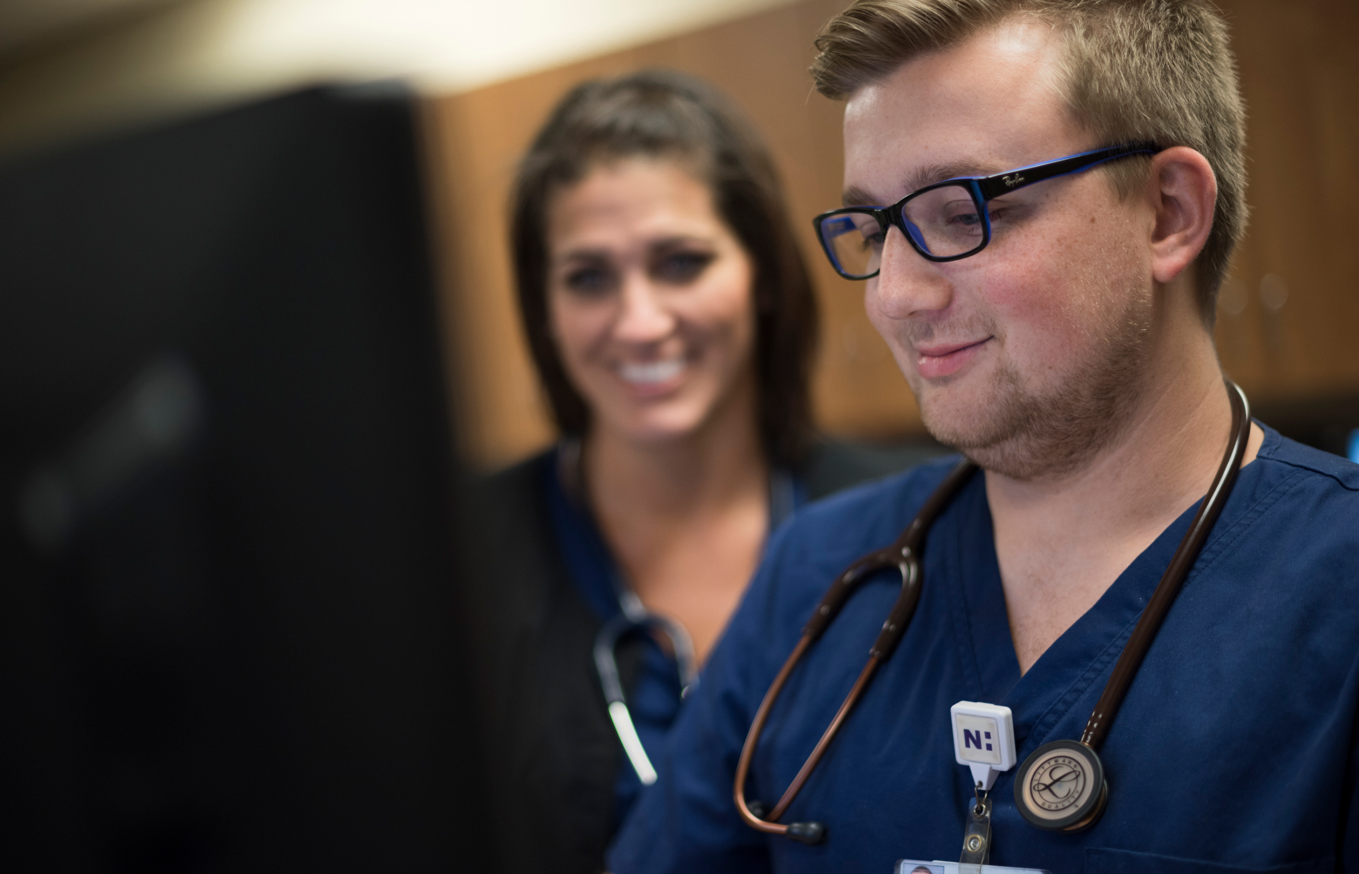 Close up of two nurses sitting at a desk review information on a computer