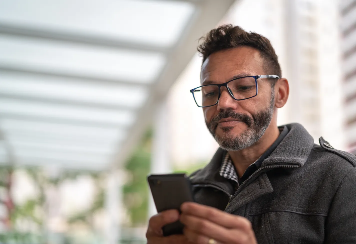 A man is outside viewing information on his smart phone. 