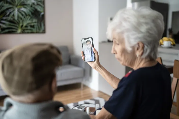 A senior couple are sitting and talking while having a virtual visit with a health care provider. 